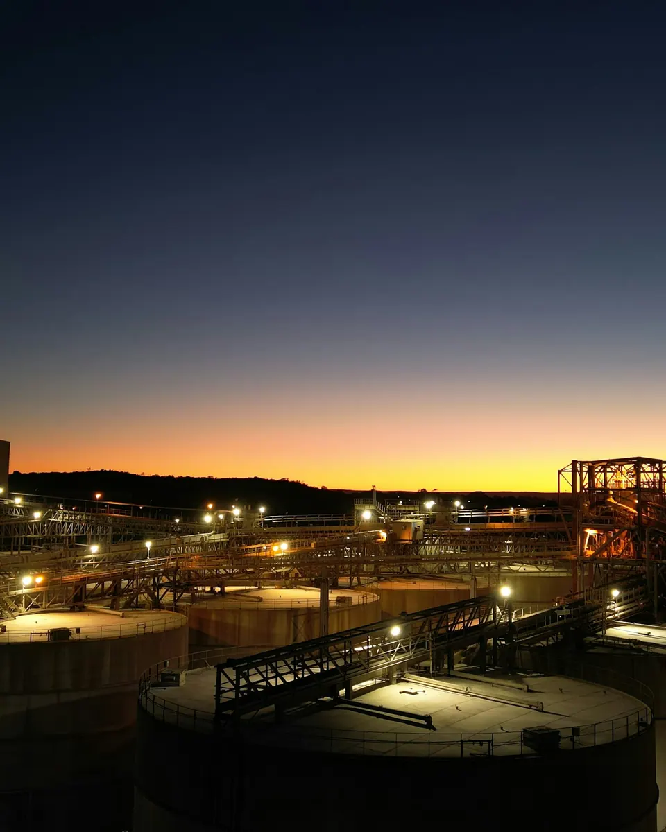 Terminal de almacenamiento con tanques cilíndricos de gran diámetro al crepúsculo.